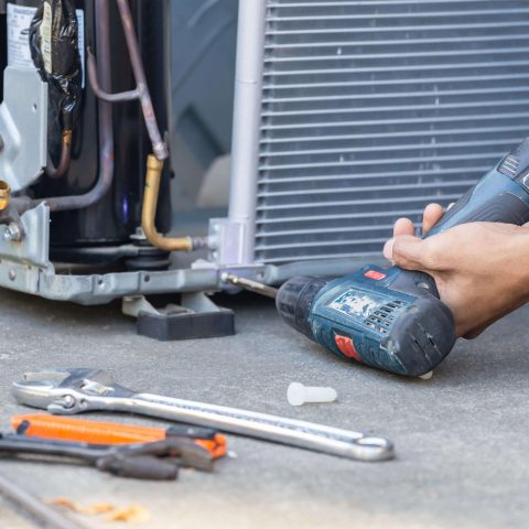 A/C repair technician fixing a broken air conditioning unit in Sterling, VA.